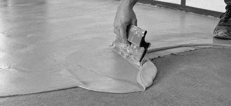 Un applicateur étale le béton ciré à la lisseuse sur un sol
