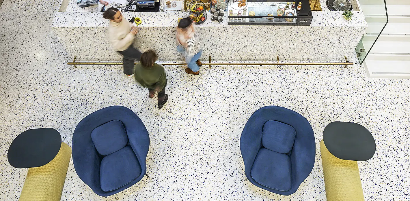 Sol en terrazzo coulé en place vu d'en haut, blanc moucheté de bleu, avec comptoir et fauteuils bleus