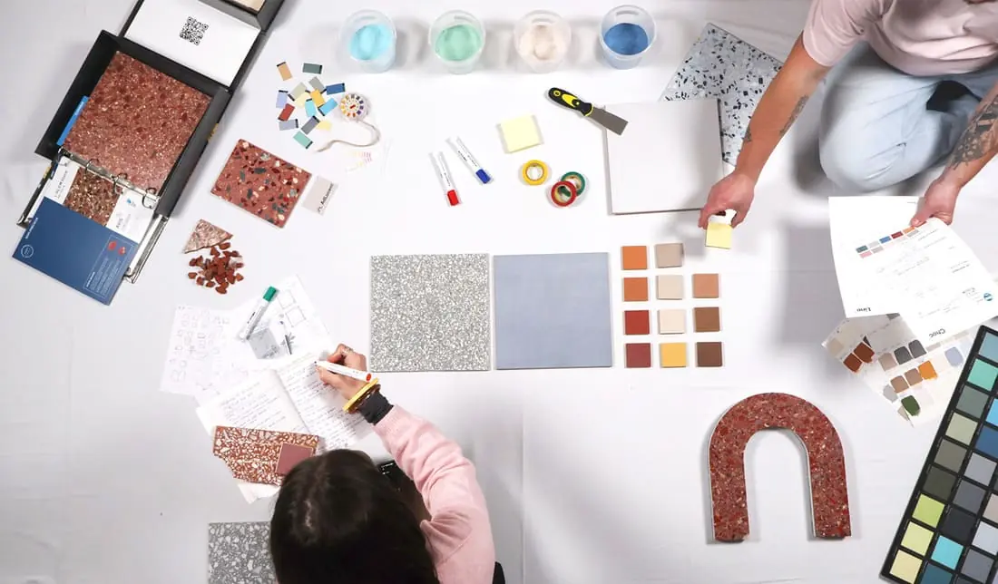 Composition d'ambiance sur une table de travail : échantillons de béton ciré et de terrazzo, nuanciers et matières