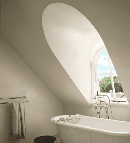 Luxury bathroom with microcement walls, arched window and freestanding bathtub