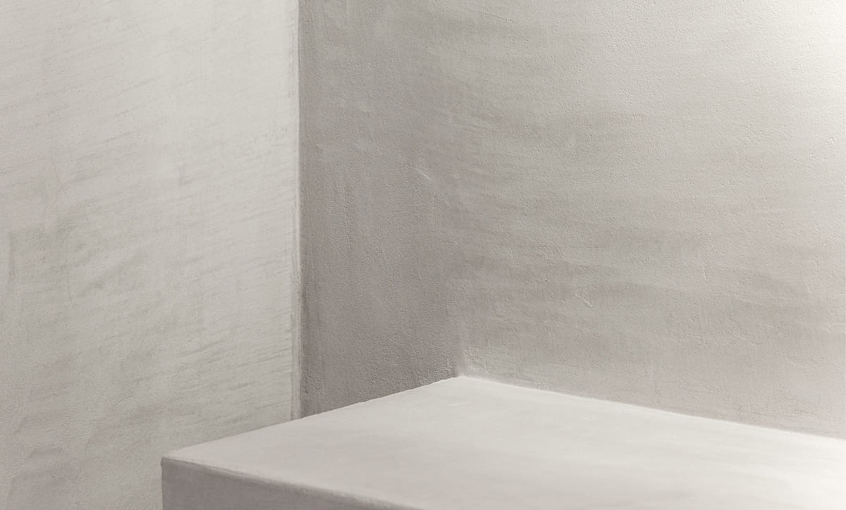 Microcement wall behind a bathroom vanity with brass fixtures