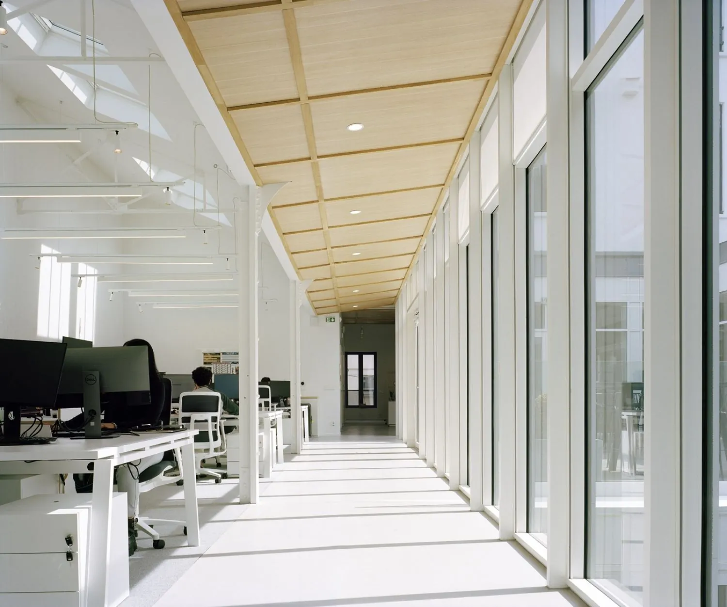 Bureaux au sol en béton ciré le long d'une circulation vitrée